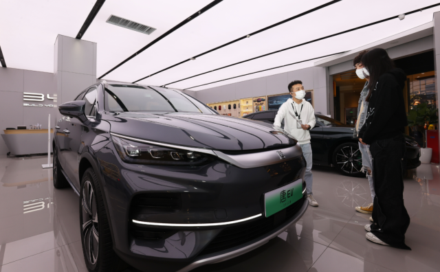 比亚迪店内，一名销售人员（左）正在向两位顾客介绍车辆信息。深圳特区报记者 杨浩翰 摄