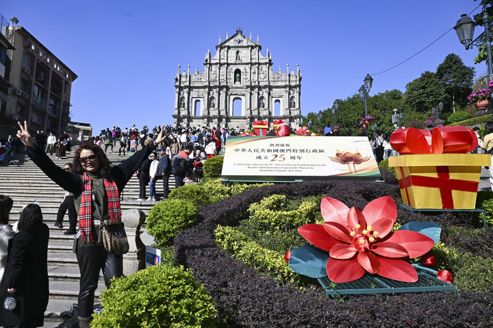 游客在澳门大三巴牌坊庆祝布景旁留影（2024年12月18日摄）。新华社记者 程一恒 摄