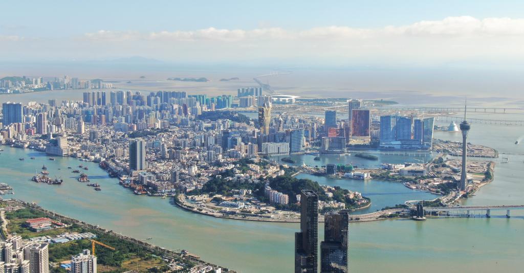 从珠海市区拍摄的澳门及远处的港珠澳大桥（2024年11月26日摄，无人机照片）。新华社记者 邓华 摄