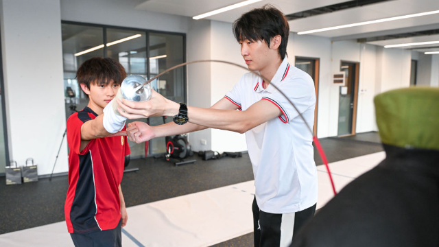 ↑图为广东现代五项运动协会教练员肖勇炫（右）纠正广州市中黄港澳子弟学校港籍生张嗣涛击剑技术细节（6月19日摄）。新华社记者肖恩楠摄