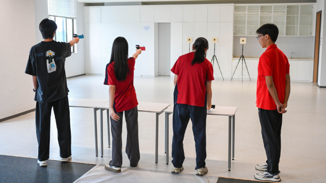 图为学生们在广州市中黄港澳子弟学校运动室进行射击训练