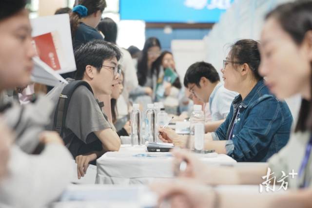 “百万英才汇南粤”武汉招聘会现场火爆，企业招聘展位座无虚席，面试洽谈对接需求。